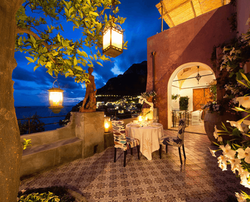 Outdoor patio with tiled floor under night sky, lit by lamps, with table