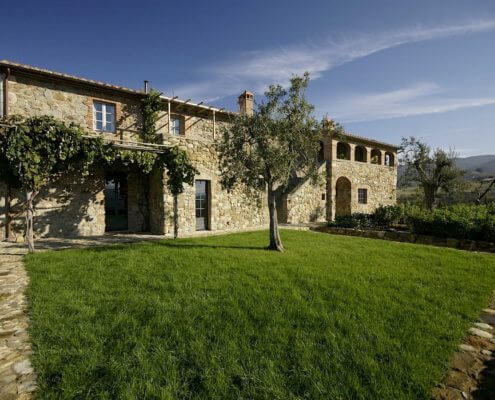 Villa Veduta in Val d'Orcia, an Italian villa with grass and a tree in front