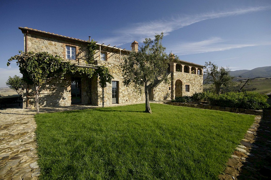 Villa Veduta in Val d'Orcia, an Italian villa with grass and a tree in front