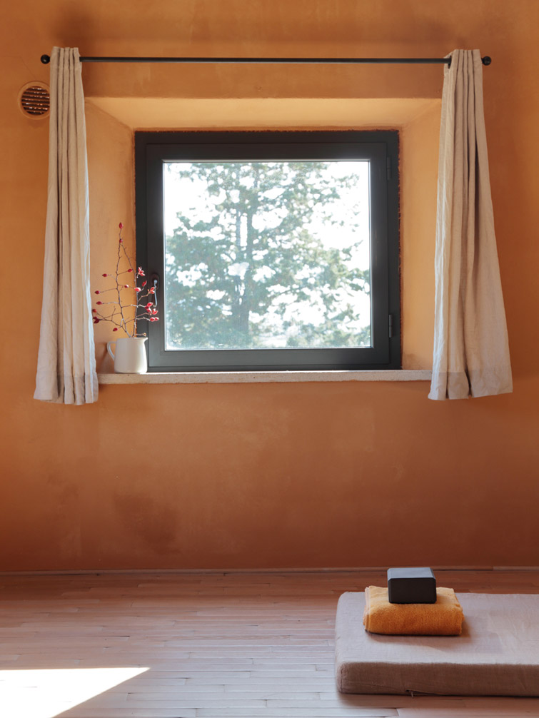 A window in a minimalist room with a yoga mat and cloth on it.