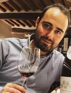 Francesco Maramai holding a glass of wine and smiling.
